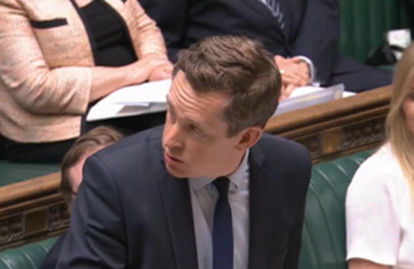 Tom participating in Home Office Questions in his role as Minister of State for Legal Migration and the Border in the House. He is turned towards a colleague, answering their question.