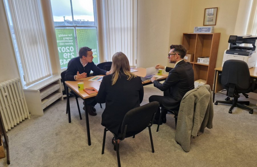 Tom in discussion with two representatives from Newlands Developments. They are all sat at a table. Tom is talking and gesturing with open hands.