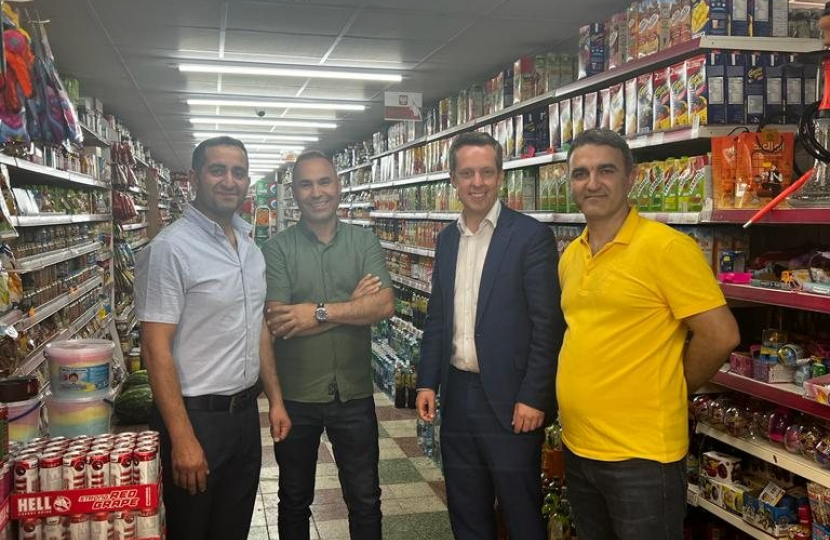 Tom stood with local shop owners in Euromarket. There are shelves full of products in the background