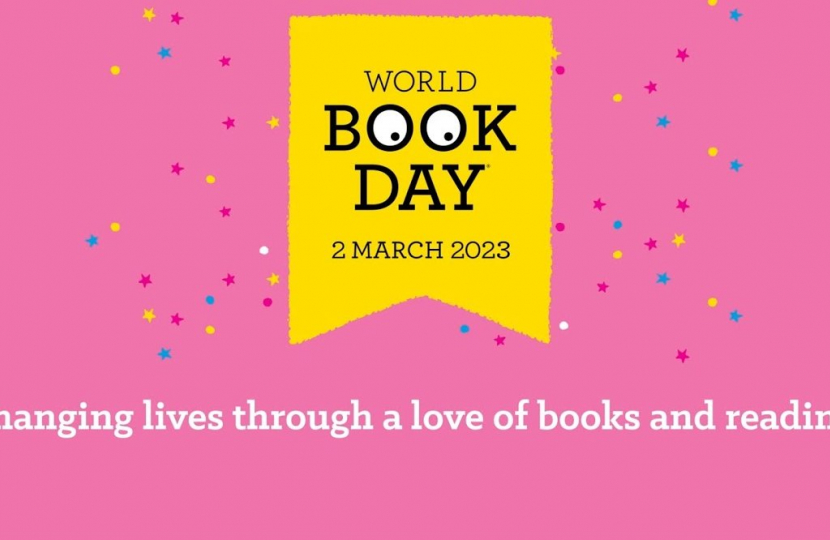 Yellow World Book Day logo on a pink background. Sentence at bottom of image reads: "Changing lives through a love of books and reading"