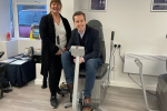 Tom Pursglove MP and Mandy Young MBE at Adrenaline Alley's A.I.M facility. Tom is sat on one of their exercise machines and Mandy is stood next to him. Both are smiling.