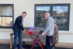 Tom Pursglove MP, with Harry, a resident at Priors Hall Care Home, unveiling the new Chatty Bench and cutting a red ribbon.