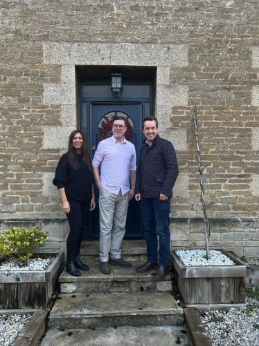 Tom stood next to the owners of The Manse Retreat. All three are stood on stone steps in front of the door into the building.