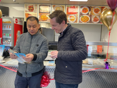 Tom Pursglove MP with a representative from Wokswagon, Oakley Vale. They are both in the restaurant and are looking through a menu together.